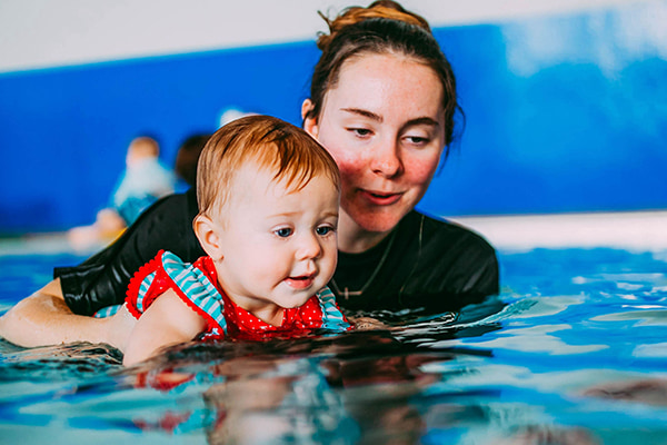 girl and toddler in pool swimming lesson