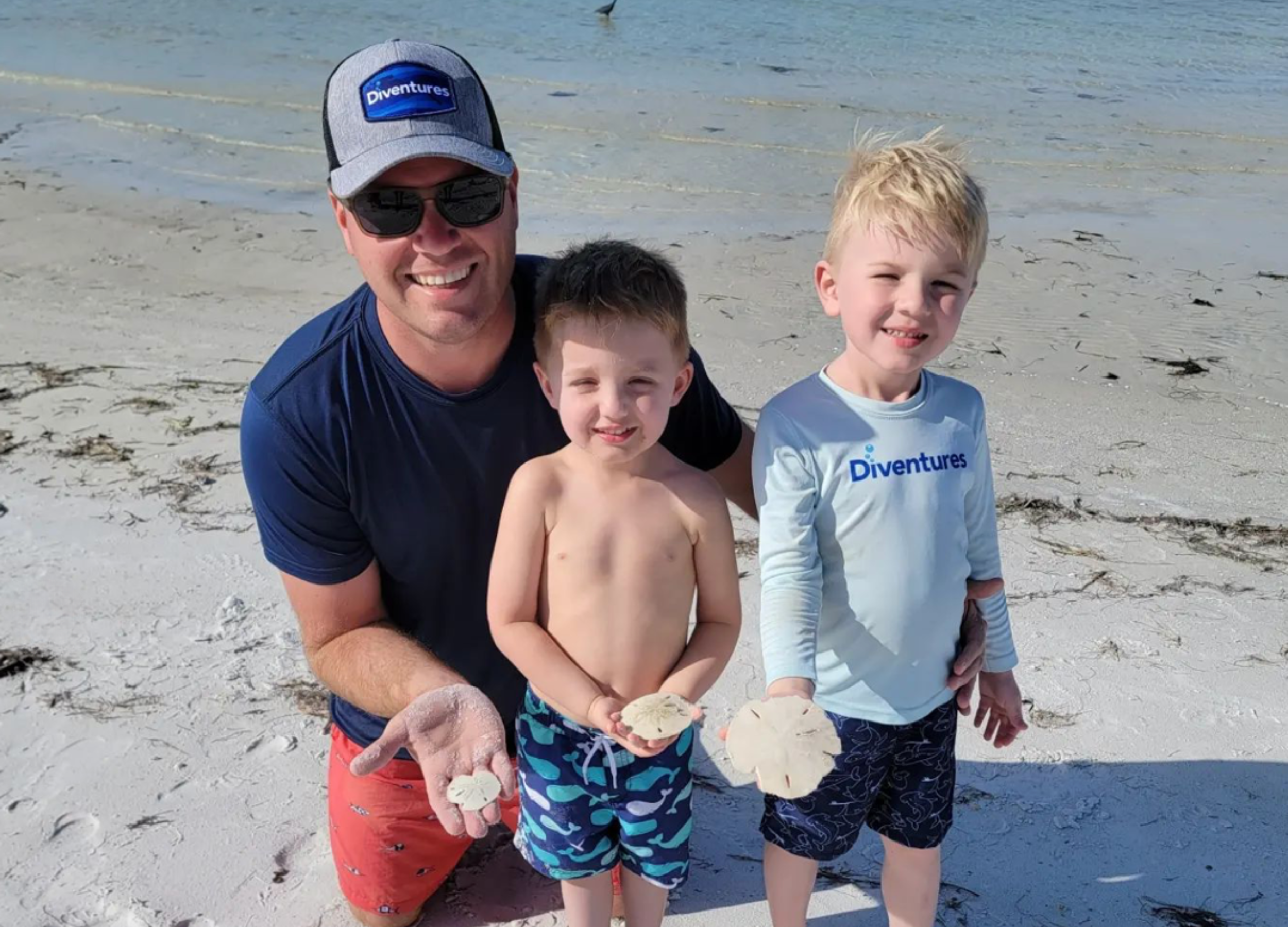 family at beach holding sand dollars