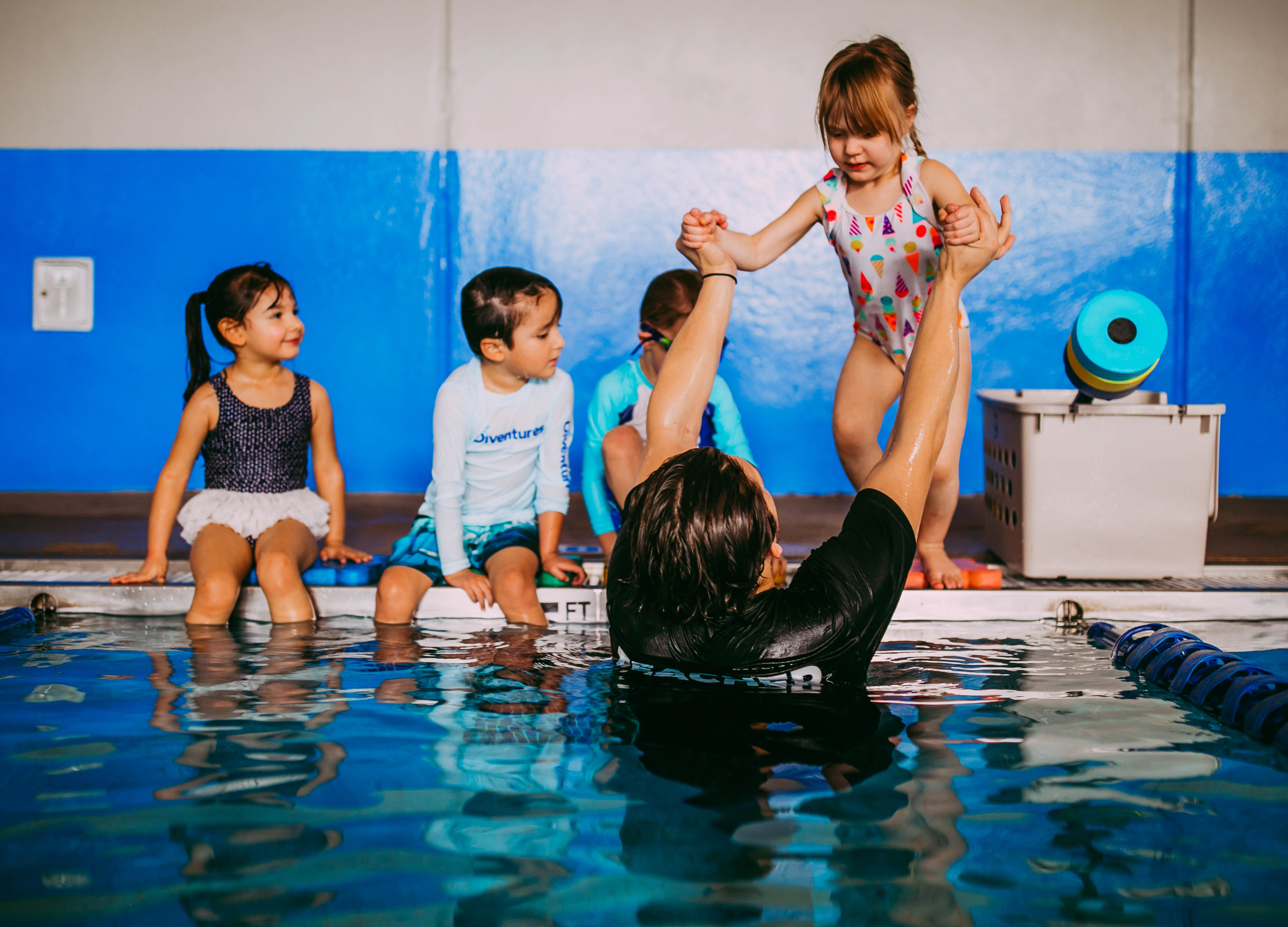 teacher helping student jump into pool